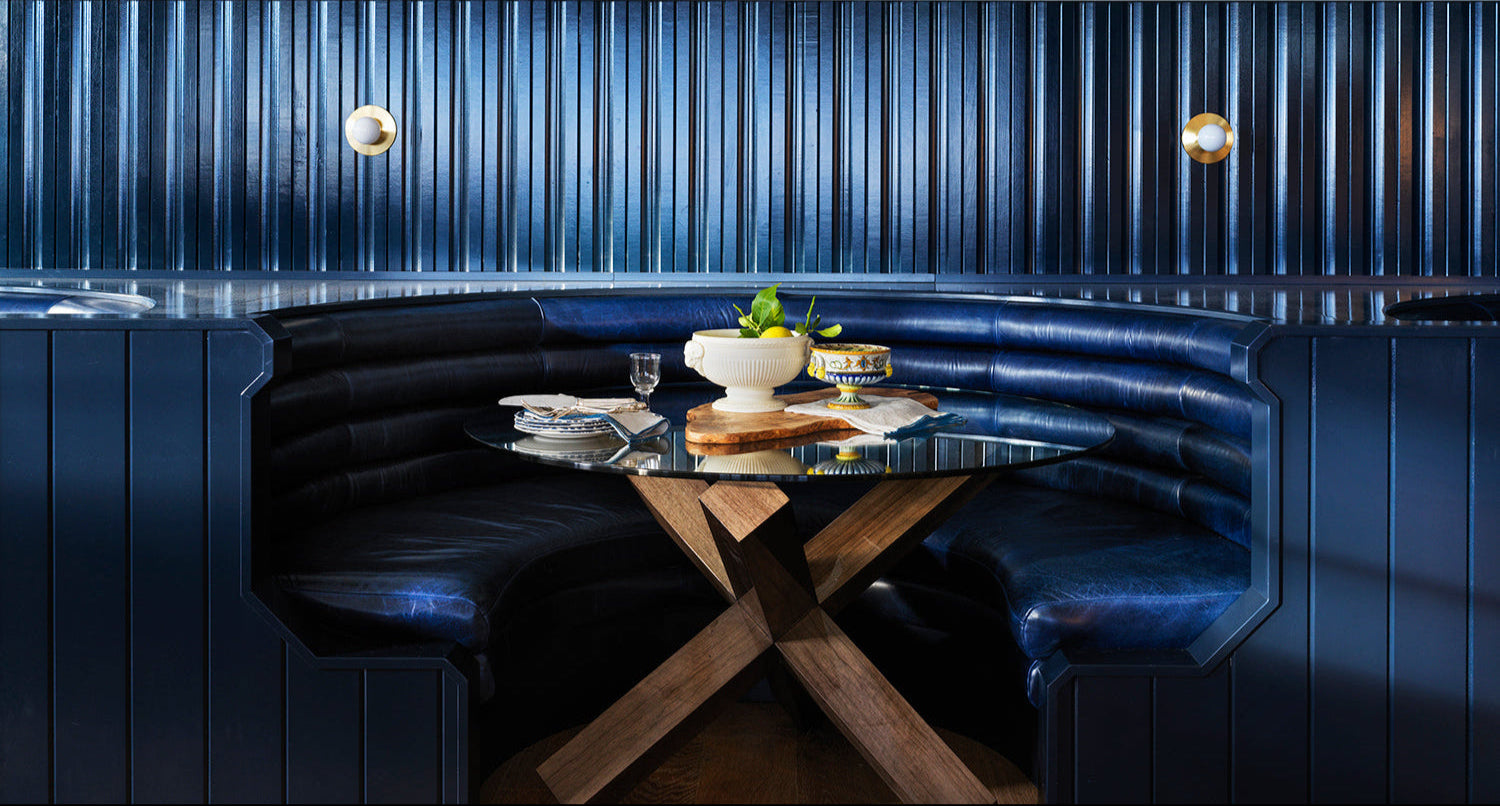 Modern dining setting with a dark blue booth and wooden table.
