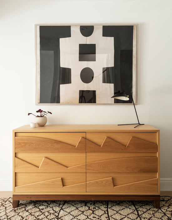 Wooden dresser with abstract art above it in a room setting

