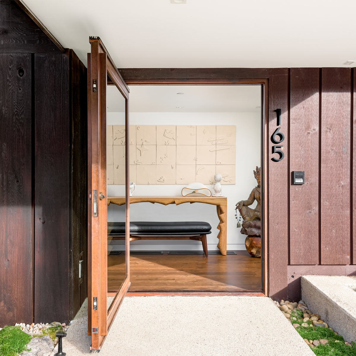 Modern house entrance with open wooden door featuring a white oak finished console table 
