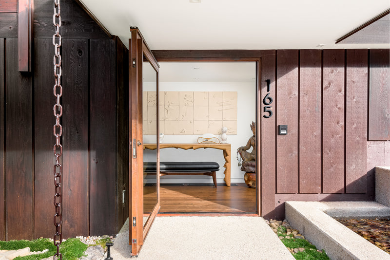 Modern house entrance with open wooden door featuring a white oak finished console table 
