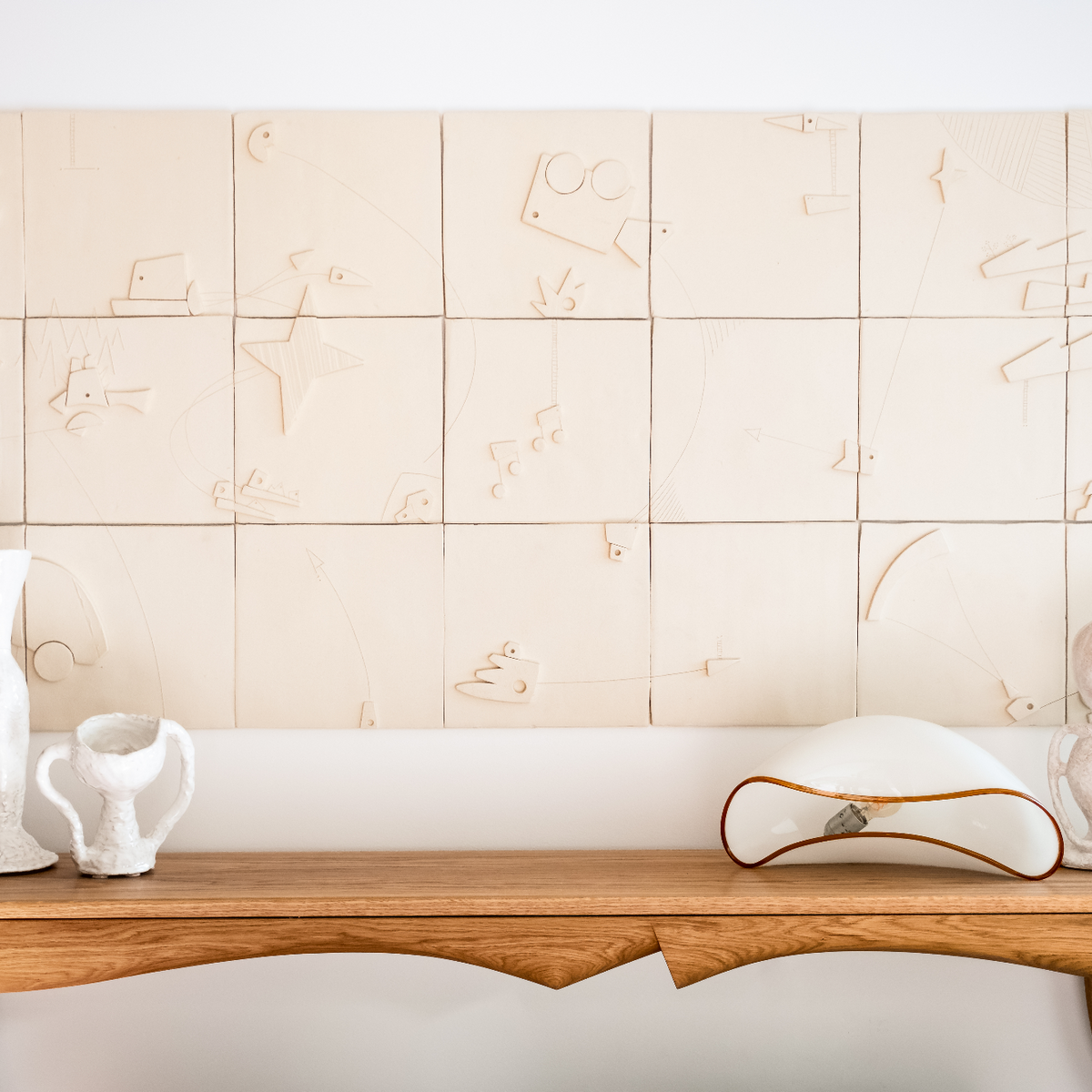 Walnut finished console table with decorative items against a tiled wall.
