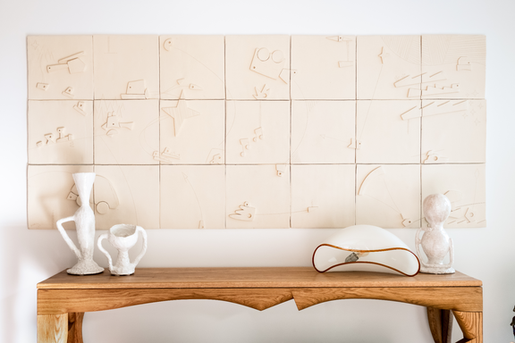 Walnut finished console table with decorative items against a tiled wall.
